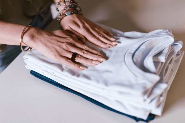 Dê Um Basta na Correria Descubra Como o Planejamento Semanal Pode Mudar Seu Dia a Dia-mãos femininas sobre uma pilha de camisas na maioria brancas