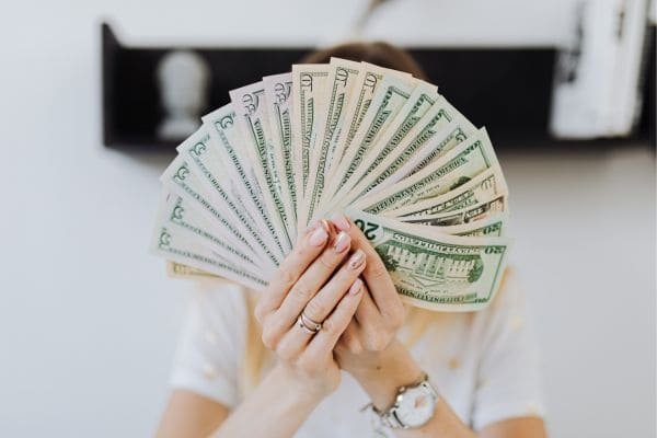 Renda extra sem sair de casa 7 ideias reais para começar ainda essa-mãos femininas segurando leque de dinheiro